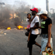 People walk past a barricade during a protest over the cost of fuel in Port-au-Prince, Haiti, Friday, July 6, 2018.
